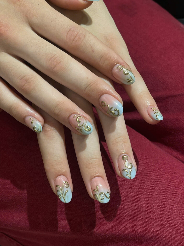 Pale blue gradient nails with gold swirl line art at Art Spa 2, Hoi An