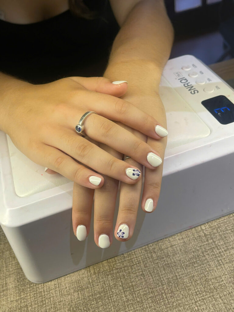 White gel nails with a navy hibiscus flower accent at Art Spa 2, Hoi An
