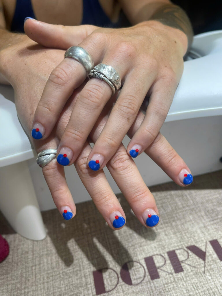 Short nails with blue half-moon tips and a small red rhinestone at Art Spa 2, Hoi An